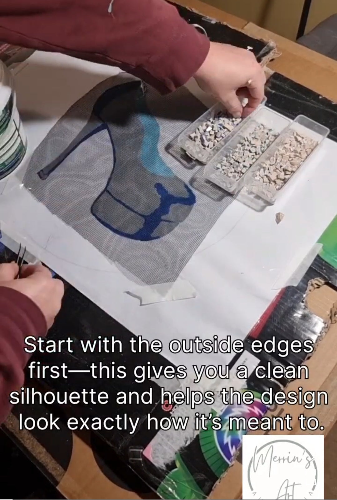 Load video: Video tutorial showing the beginning of a mosaic project, starting with tiling the outside edge. The artist carefully places and adjusts tiles along the border, explaining the importance of framing the design before working inward.