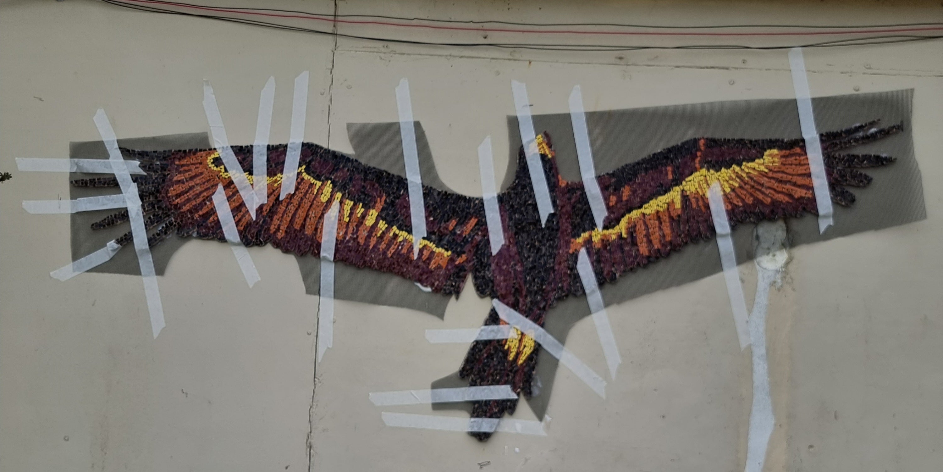 Wedge-tailed eagle mosaic installed and held up with making tap while it dries for sale