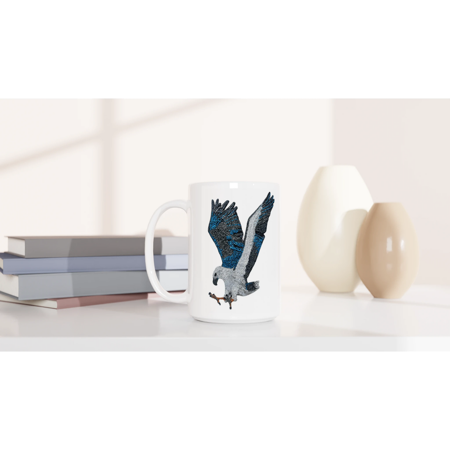 willow the white-bellied sea eagle mosaic design printed on white ceramic mug displayed in a lifestyle setting with books and vases