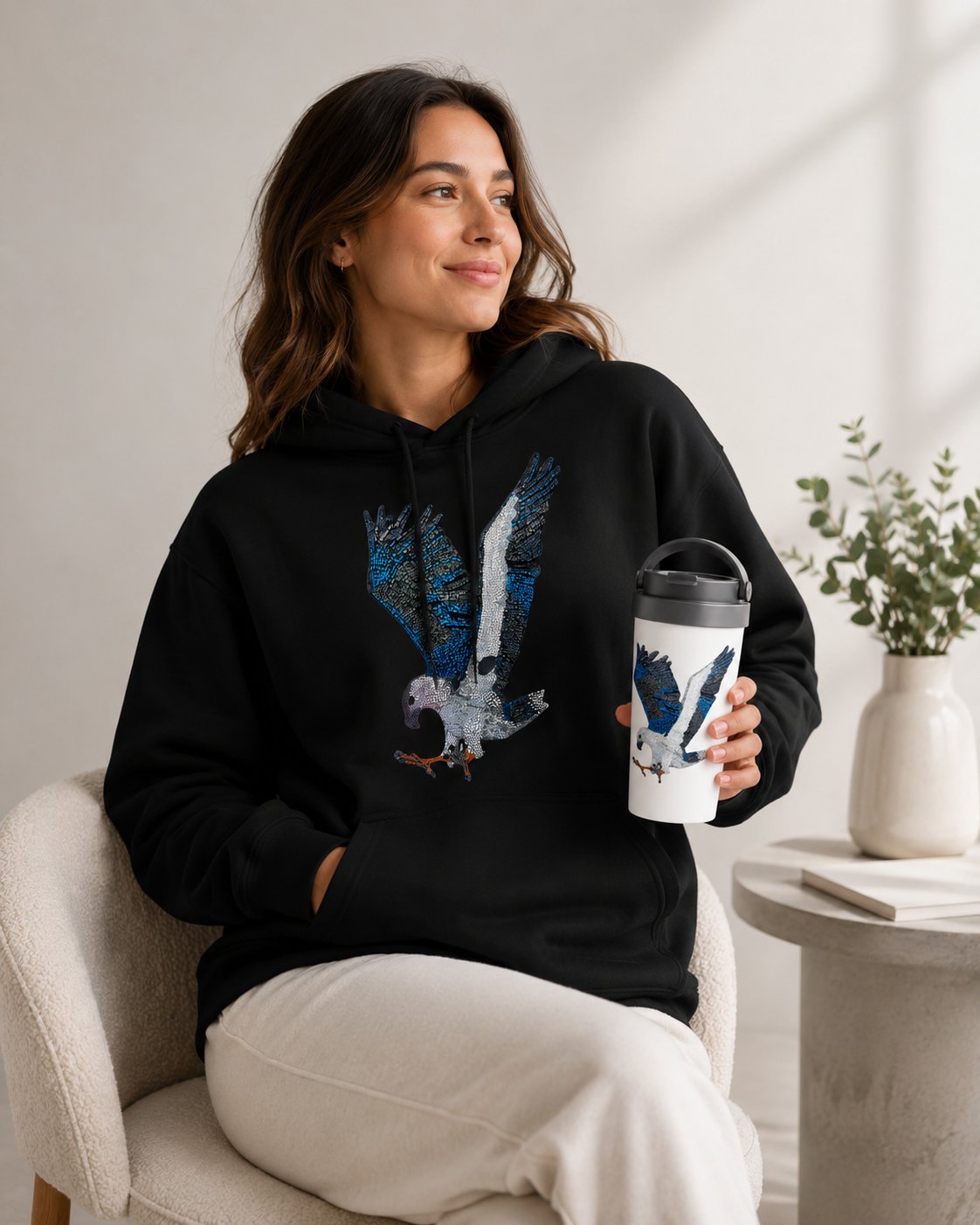 Willow the white-bellied sea eagle mosaic travel mug and hoodie modelling indoors 