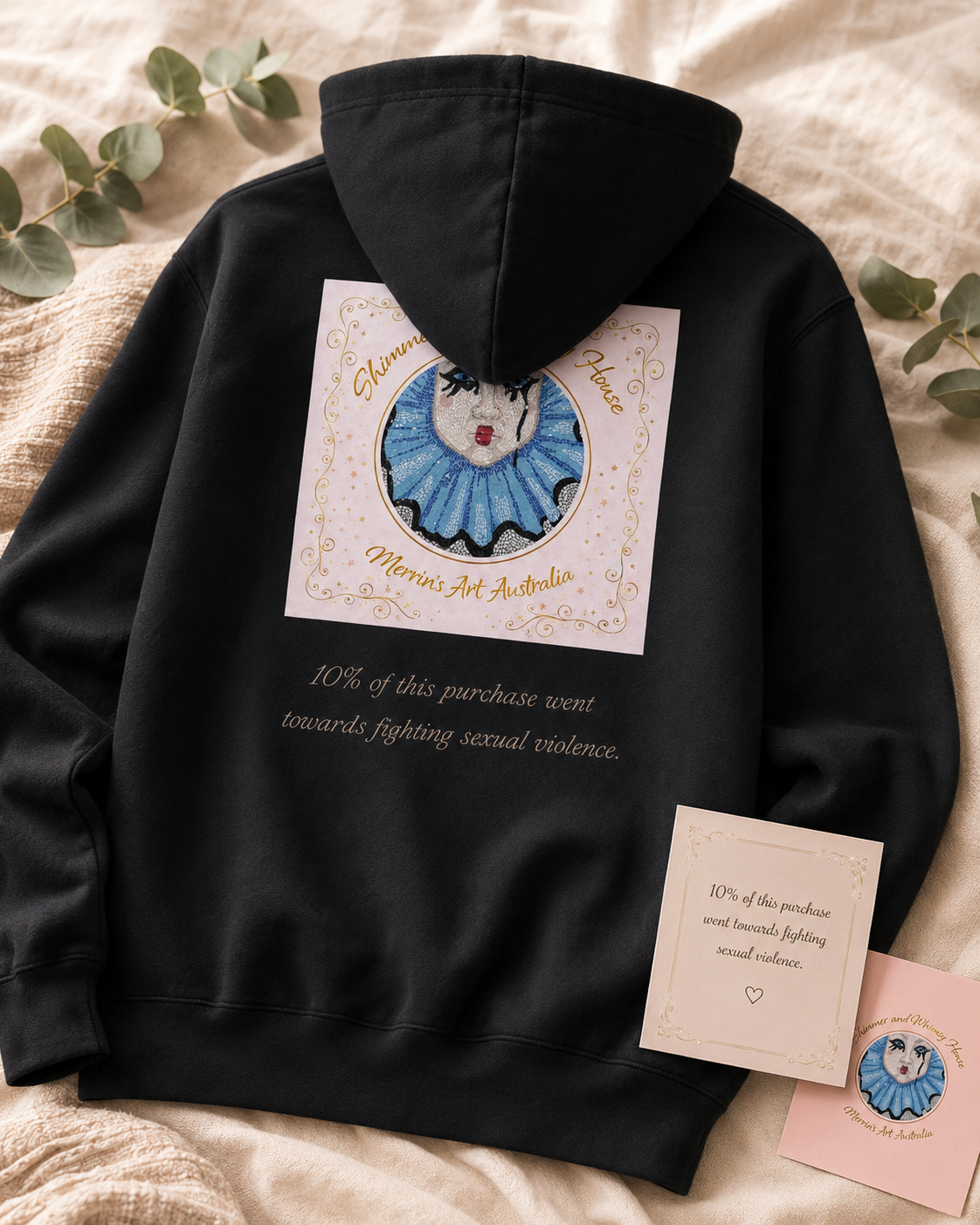 Back view of the black Willow hoodie showing the Shimmer and Whimsy House logo under the hood and the giving message, “10% of this purchase went towards fighting sexual violence.”