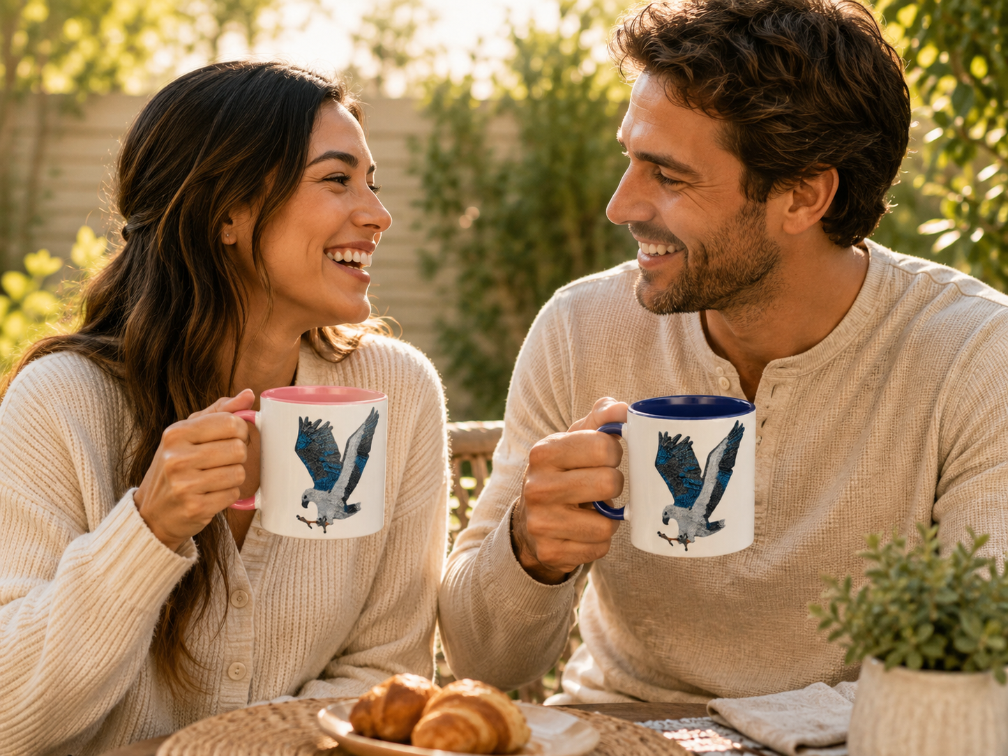 Two people enjoying Willow White-bellied Sea Eagle mosaic mugs outdoors in a relaxed garden setting, laughing together in golden natural light with the mug artwork visible.